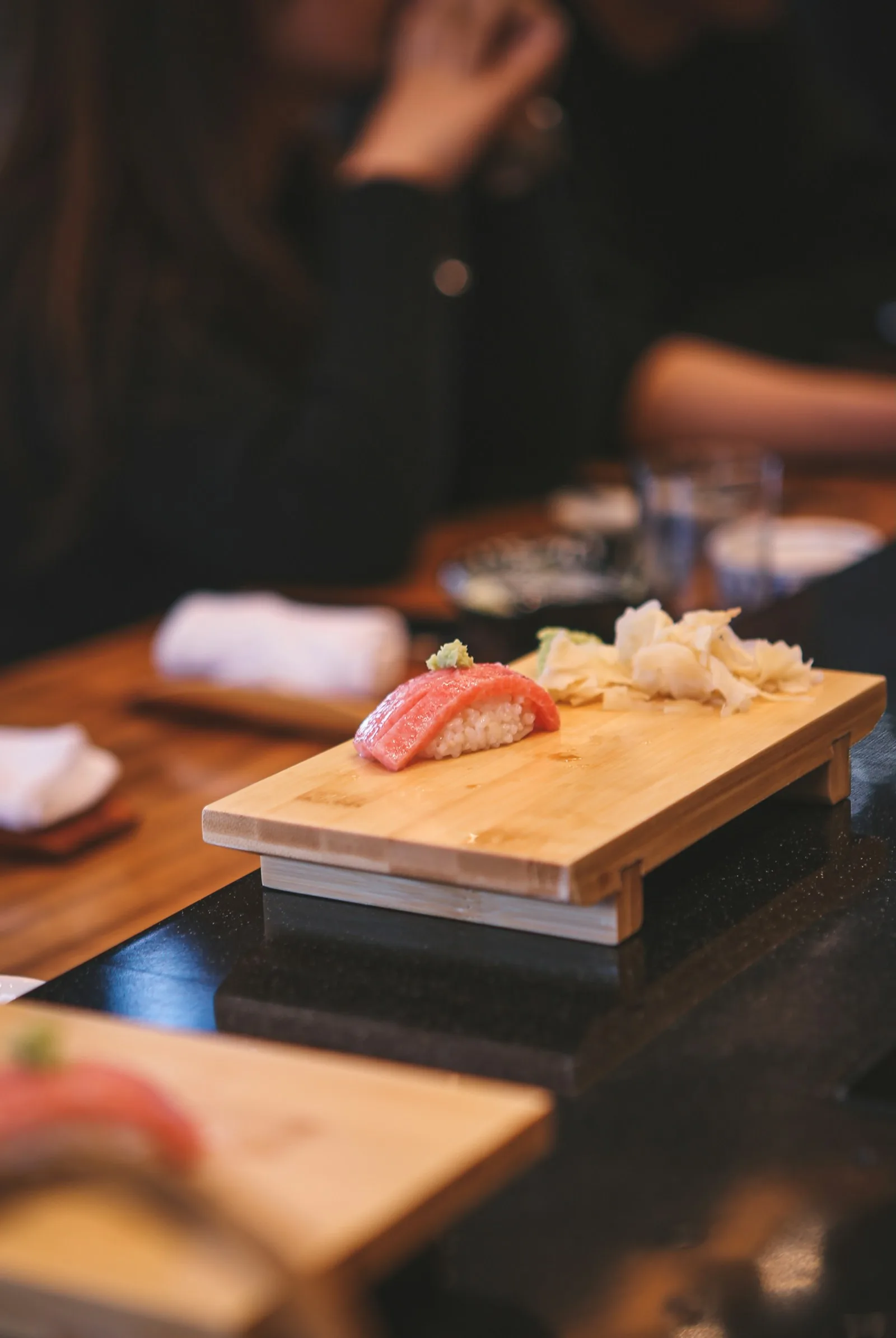 Tuna nigiri with ginger and wasabi served on a wooden plate